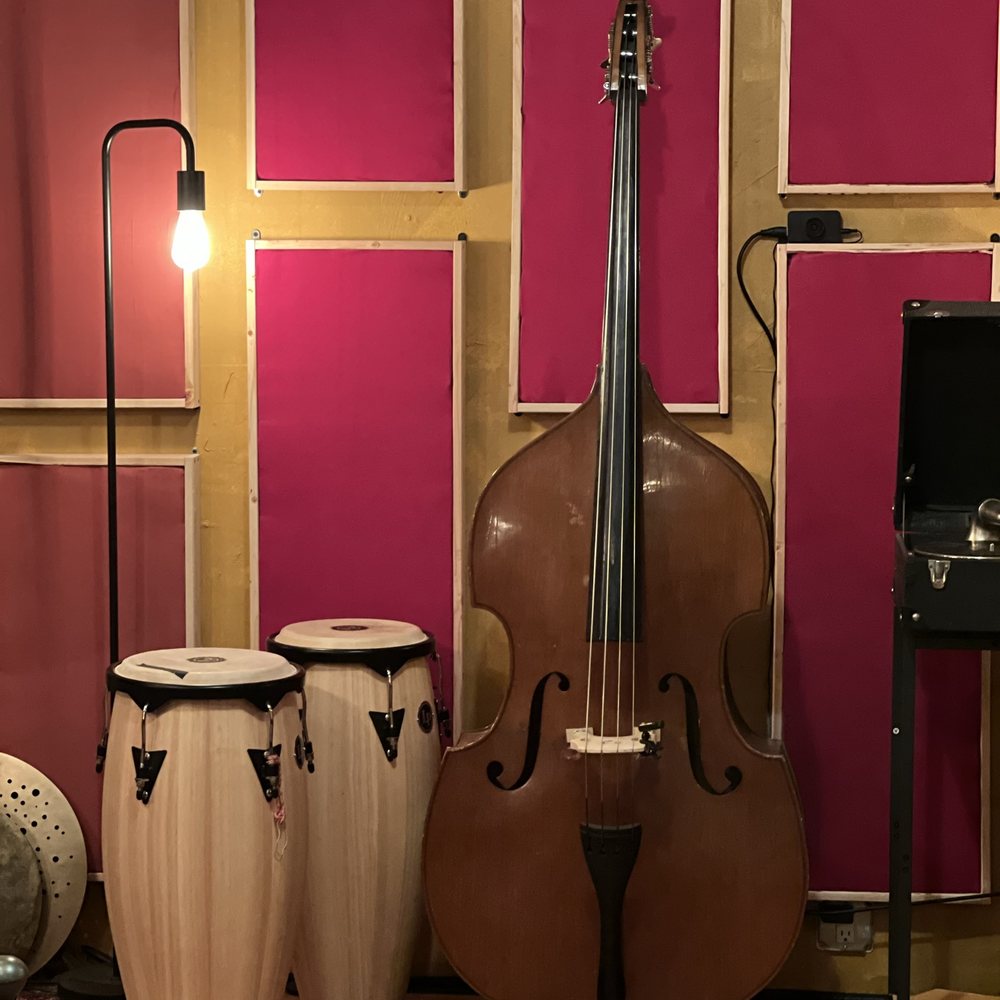 An upright double bass standing in the studio, its carved wooden body and strings lit in warm light